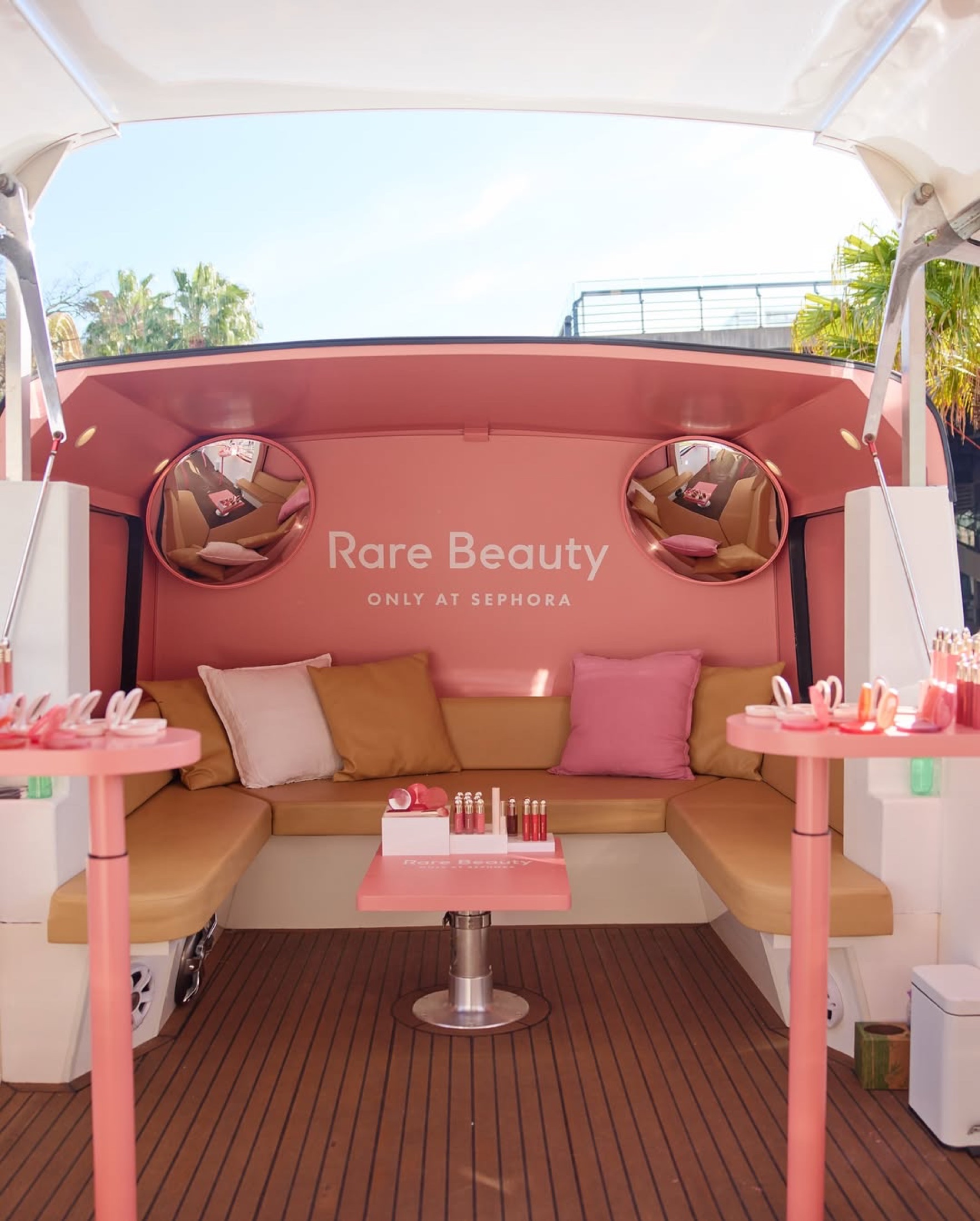 Branded upper-deck lounge inside the Rare Beauty bus